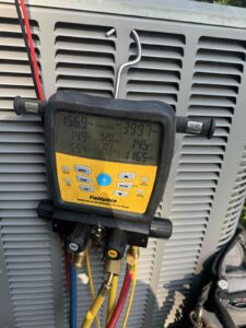 Digital HVAC manifold gauge connected to an outdoor AC unit