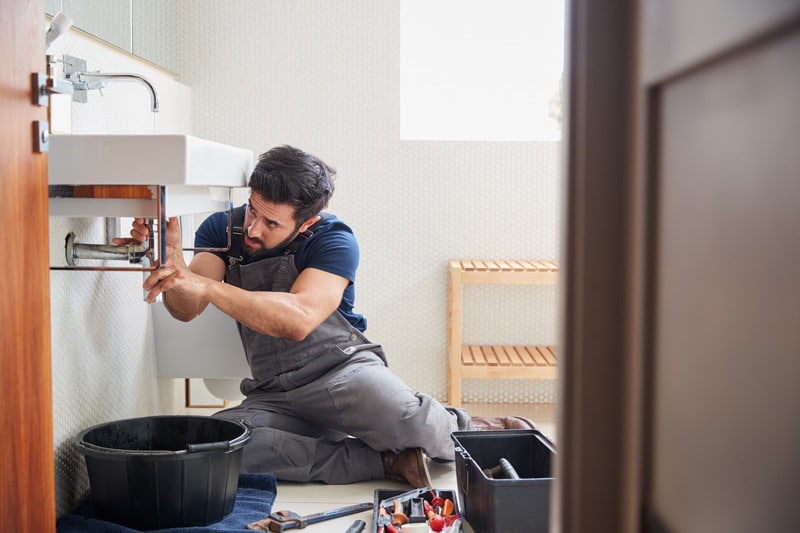 Plumber performing professional drain cleaning in a home